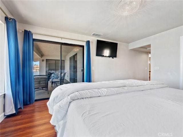 bedroom with dark hardwood / wood-style flooring, a notable chandelier, and access to outside