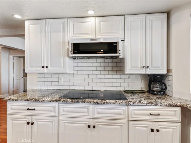 kitchen with tasteful backsplash, white cabinets, and black electric cooktop