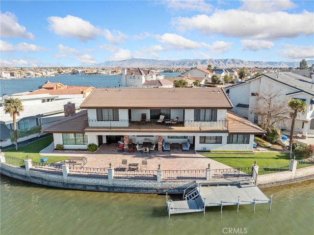 back of property featuring a patio area, a water and mountain view, and a lawn