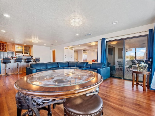 dining area with a textured ceiling and light hardwood / wood-style floors