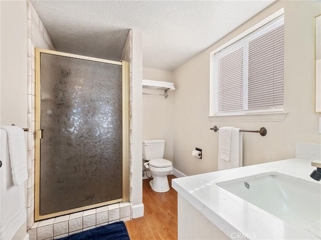 bathroom featuring hardwood / wood-style flooring, vanity, walk in shower, toilet, and a textured ceiling