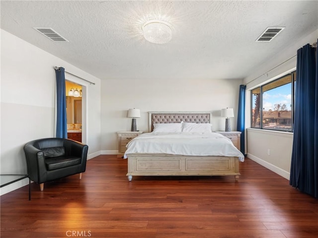 bedroom with connected bathroom, dark hardwood / wood-style flooring, and a textured ceiling