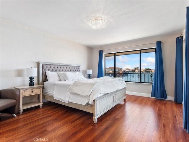 bedroom featuring a water view and dark wood-type flooring