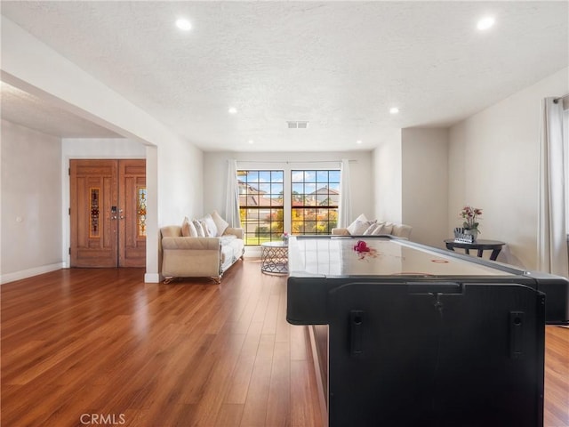 recreation room with light hardwood / wood-style floors and a textured ceiling