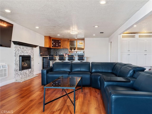 living room featuring wood-type flooring, a wall unit AC, and a textured ceiling