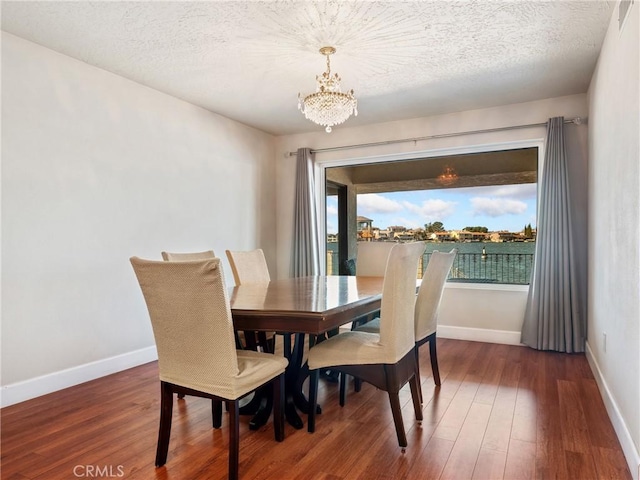 dining space featuring dark wood-type flooring, an inviting chandelier, and a textured ceiling