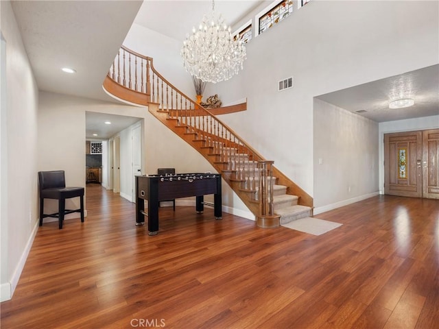 foyer with an inviting chandelier, a towering ceiling, and wood-type flooring