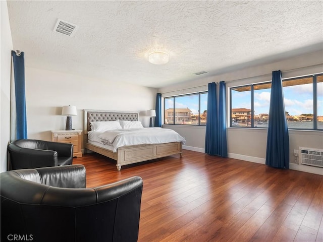 bedroom featuring a wall mounted air conditioner, dark hardwood / wood-style floors, and a textured ceiling