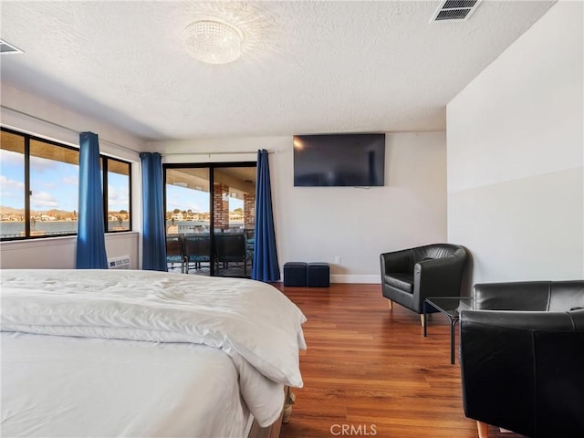 bedroom featuring hardwood / wood-style flooring, access to outside, and a textured ceiling