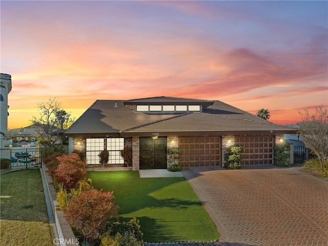 prairie-style house featuring a garage and a yard