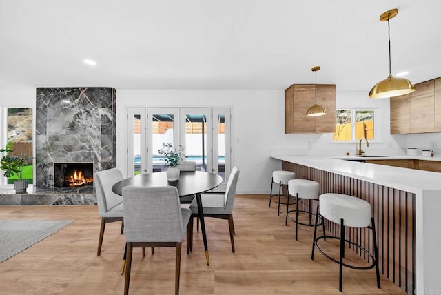 dining room with french doors, a fireplace, sink, and light wood-type flooring