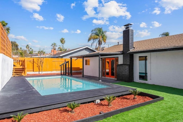 view of swimming pool with a lawn, a deck, and french doors