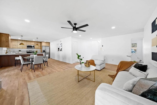 living room featuring sink, light hardwood / wood-style floors, and ceiling fan