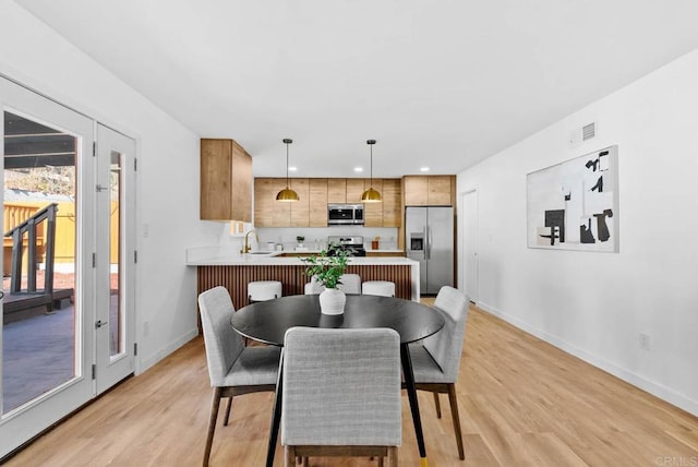 dining space with sink and light hardwood / wood-style flooring