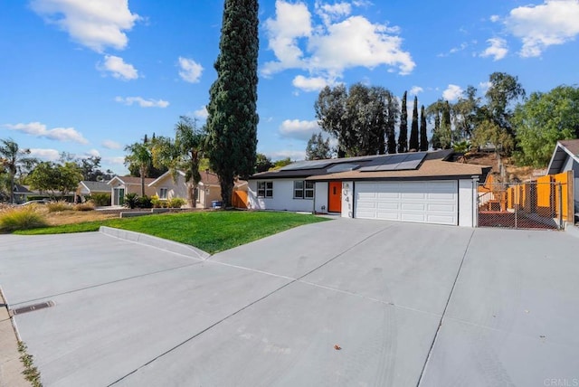 single story home featuring a garage, a front yard, and solar panels