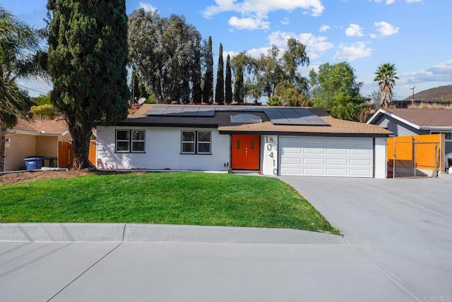 ranch-style house with a garage, a front yard, and solar panels