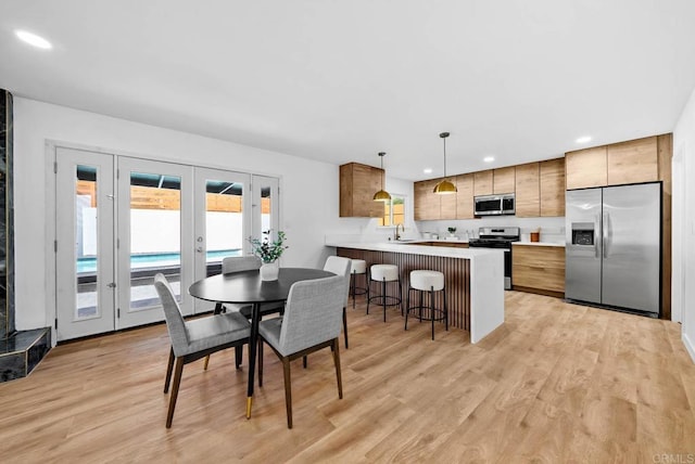 dining space with light wood-type flooring and french doors