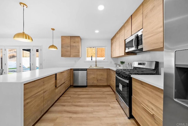 kitchen featuring appliances with stainless steel finishes, hanging light fixtures, light hardwood / wood-style floors, kitchen peninsula, and french doors