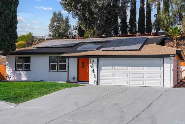 ranch-style house with a garage, a front yard, and solar panels