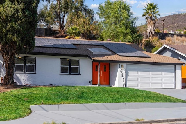 single story home featuring a garage, a front yard, and solar panels