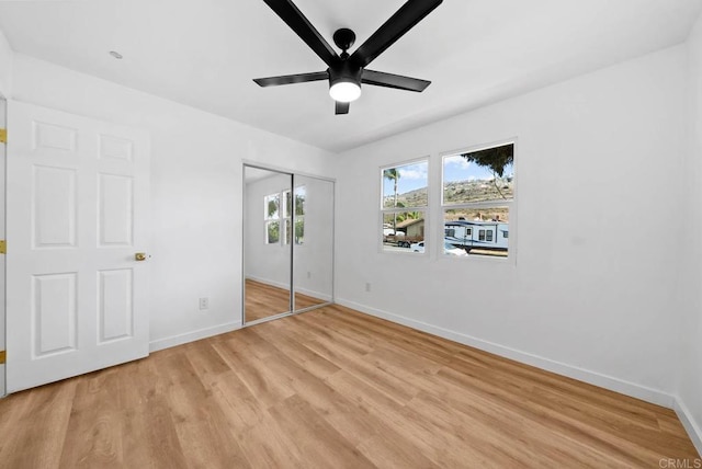 unfurnished bedroom featuring ceiling fan, a closet, and light wood-type flooring