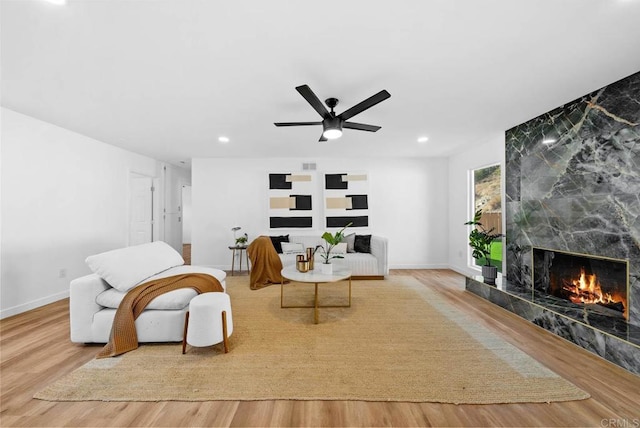 living area featuring ceiling fan, a premium fireplace, and light wood-type flooring