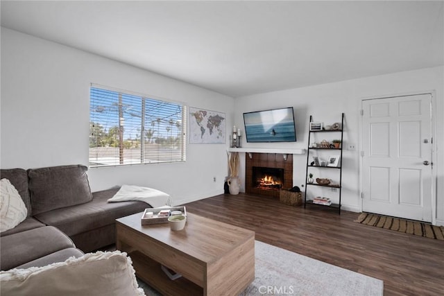 living room featuring baseboards, a warm lit fireplace, and wood finished floors