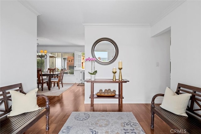 sitting room featuring a notable chandelier, wood finished floors, baseboards, and ornamental molding