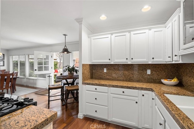 kitchen with plenty of natural light, tasteful backsplash, white cabinets, and dark wood finished floors