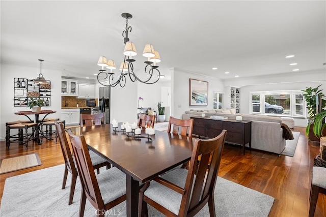 dining space featuring recessed lighting, an inviting chandelier, and wood finished floors