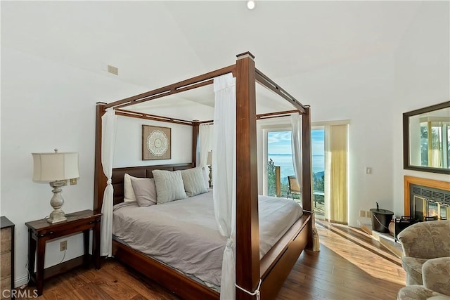 bedroom with dark hardwood / wood-style floors, a towering ceiling, and access to exterior