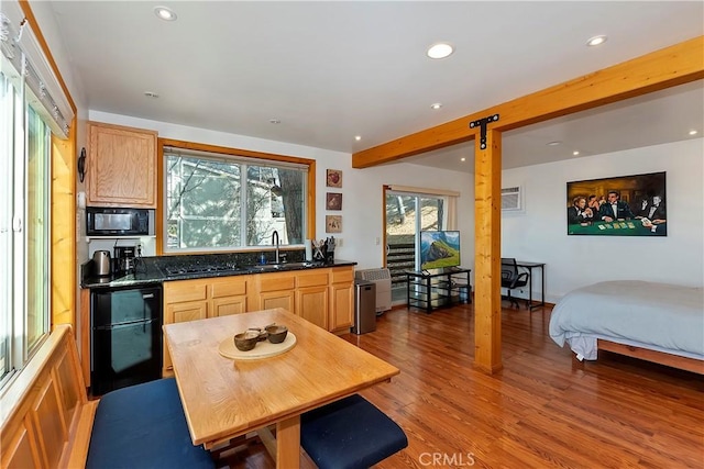 kitchen featuring beam ceiling, light brown cabinetry, sink, and black microwave