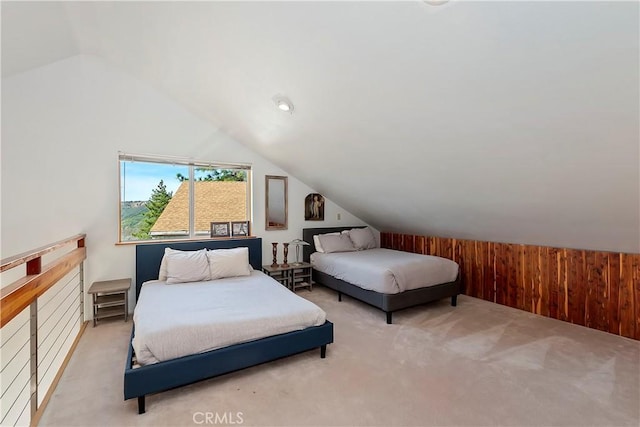 carpeted bedroom with lofted ceiling and wooden walls