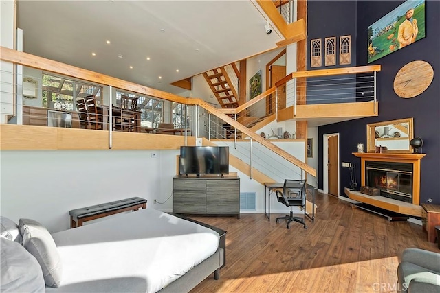 bedroom featuring a towering ceiling and hardwood / wood-style flooring