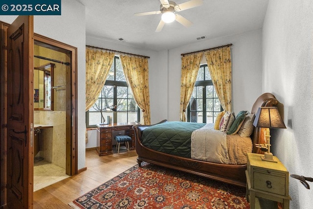 bedroom with ceiling fan, ensuite bathroom, multiple windows, and light wood-type flooring