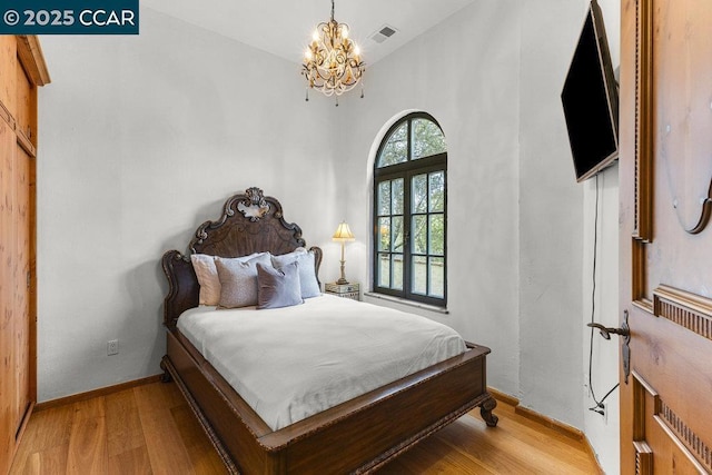 bedroom featuring an inviting chandelier and light hardwood / wood-style floors