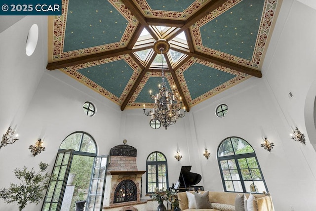 living room with a brick fireplace, a notable chandelier, plenty of natural light, and high vaulted ceiling