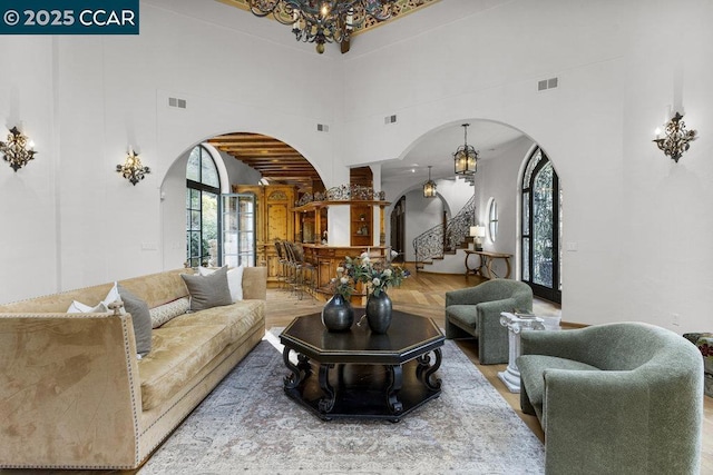 living room with a healthy amount of sunlight, a towering ceiling, and an inviting chandelier