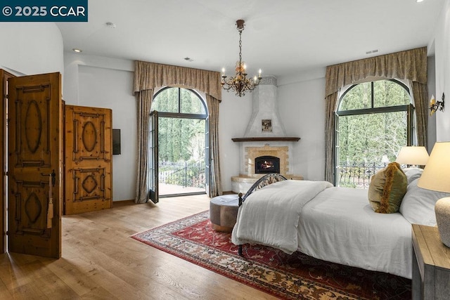 bedroom featuring multiple windows, light wood-type flooring, access to exterior, and a fireplace