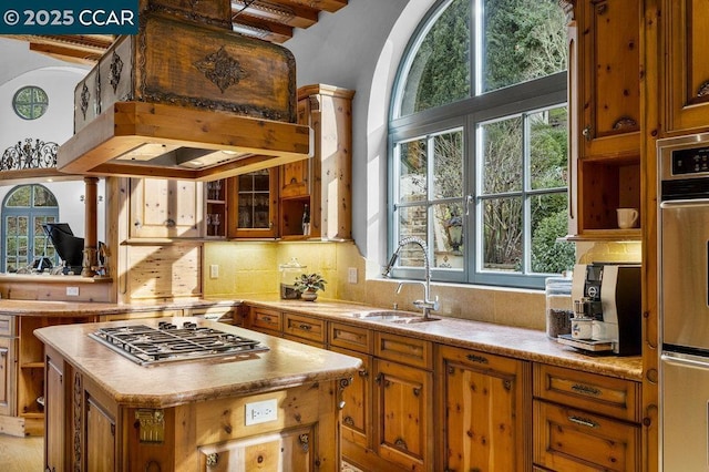 kitchen with sink, a center island, stainless steel gas cooktop, a healthy amount of sunlight, and custom range hood