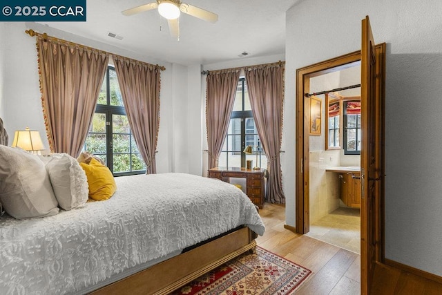 bedroom with light wood-type flooring, ceiling fan, and ensuite bath