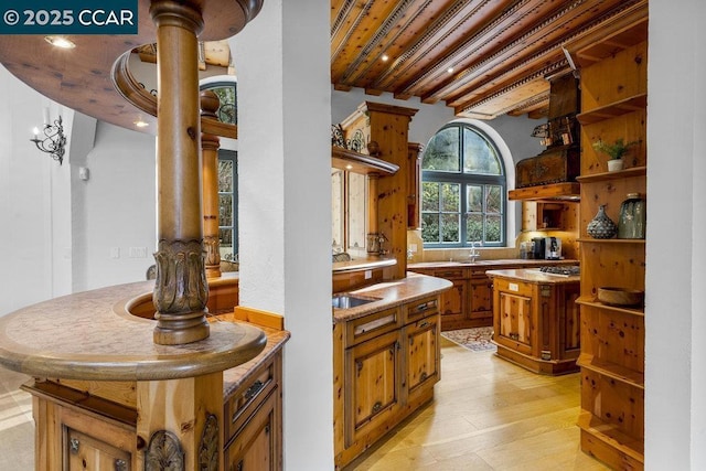 kitchen featuring light hardwood / wood-style floors, sink, a center island, and decorative columns