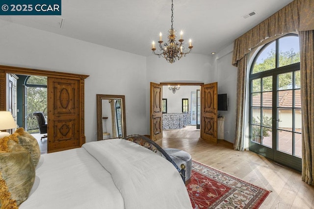 bedroom with an inviting chandelier, light hardwood / wood-style flooring, and french doors