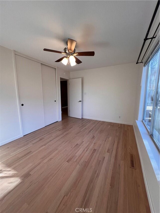 unfurnished bedroom featuring light hardwood / wood-style flooring, a closet, and ceiling fan