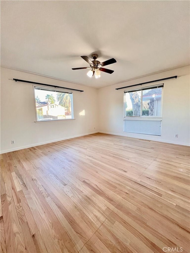 spare room with plenty of natural light, light hardwood / wood-style floors, and ceiling fan