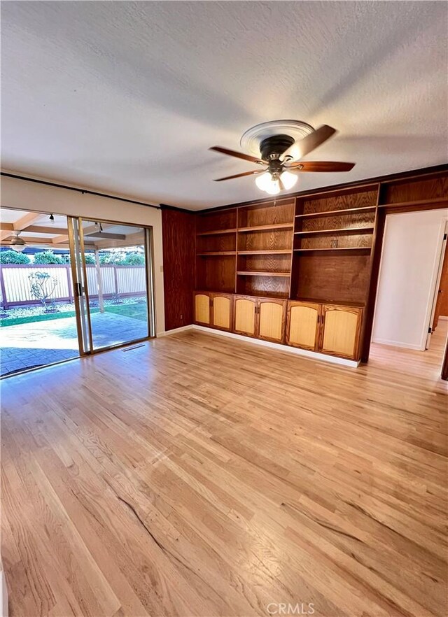 interior space with ceiling fan, light wood-type flooring, built in features, and a textured ceiling