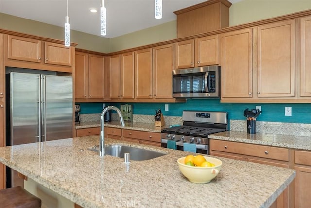 kitchen with sink, a breakfast bar area, pendant lighting, stainless steel appliances, and light stone countertops