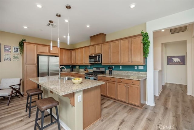 kitchen featuring appliances with stainless steel finishes, a breakfast bar, pendant lighting, an island with sink, and sink