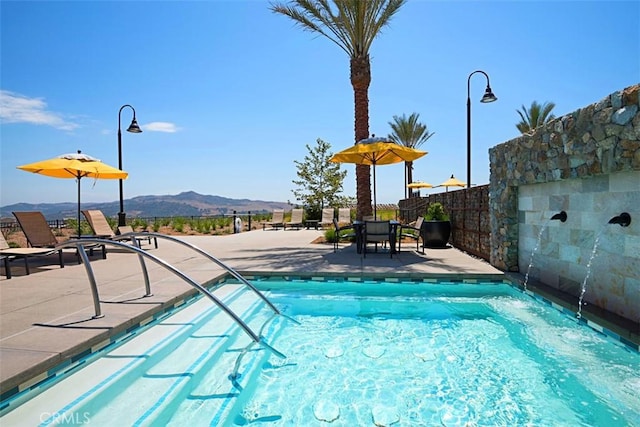 view of swimming pool with a mountain view and a patio