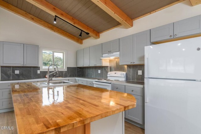 kitchen featuring white appliances, butcher block counters, under cabinet range hood, and a sink